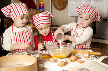 Three little chefs enjoying in the kitchen making big mess. Litt